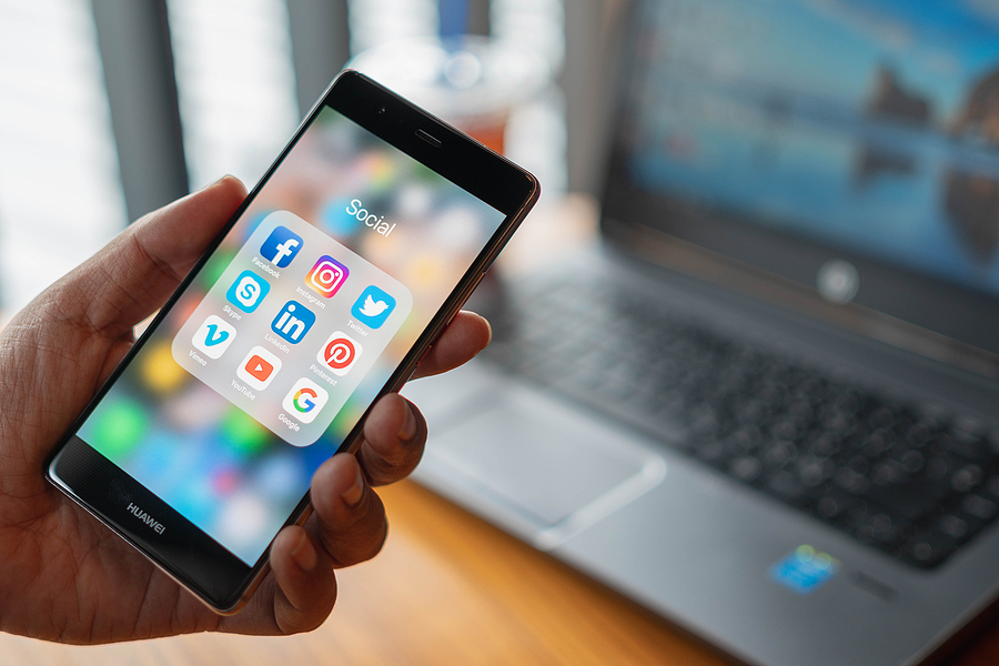 Close up of a man's hand holding a smart phone with social media apps. 